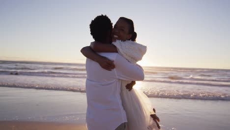 Una-Pareja-Afroamericana-Enamorada-De-Casarse,-Abrazándose-En-La-Playa-Al-Atardecer