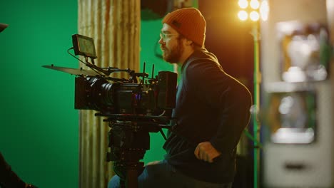 portrait of cameraman on railway trolley shooting green screne scene. professional crew on big budget filmmaking. on film studio set shooting period movie green screen scene. slow motion arc shot