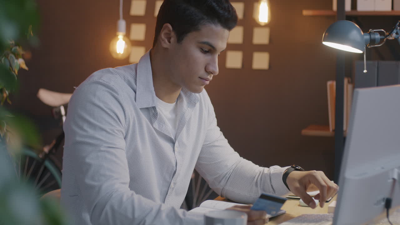 Young man working on a computer and using credit card