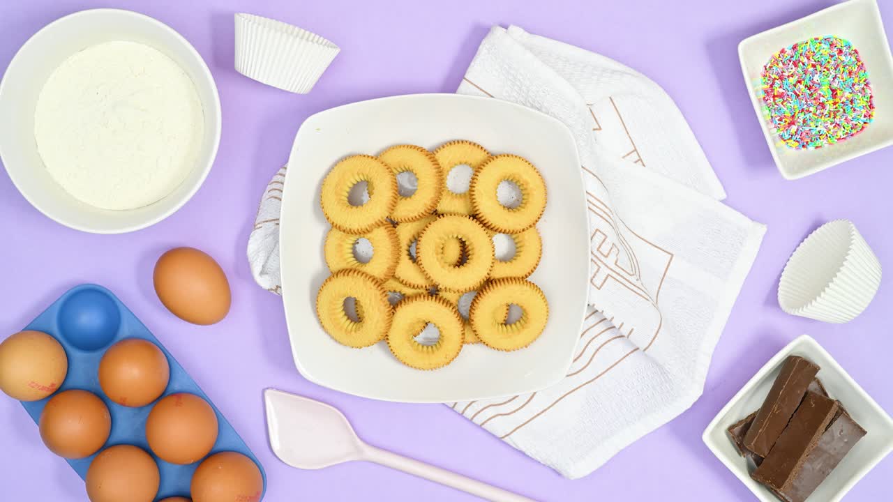 쿠키와 베이킹 재료와 식료품을 가진 접시가 밝은 보라색 테마에 나타납니다.