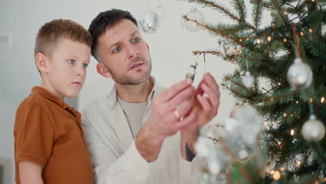papá y el niño decoran el árbol juntos.