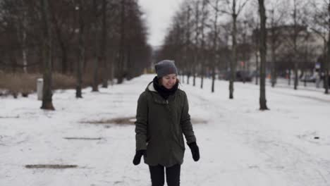 niña en el parque en invierno alcanzando para recoger la nieve del suelo, cámara lenta