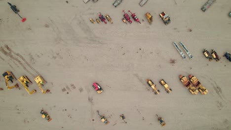 top-down aerial of aligned construction equipment on a huge industrial yard