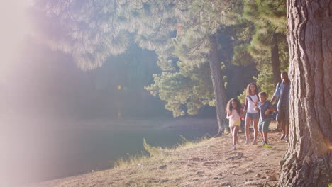 Family-On-Hike-Walking-Along-Path-Through-Woods-Next-To-Lake