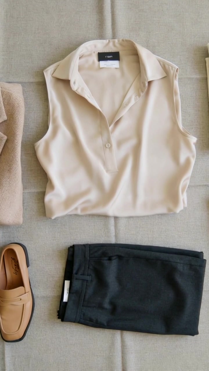 Video verticale: Ripresa dall'alto, che mostra una blusa beige centrata su un tessuto, pantaloni e mocassini.