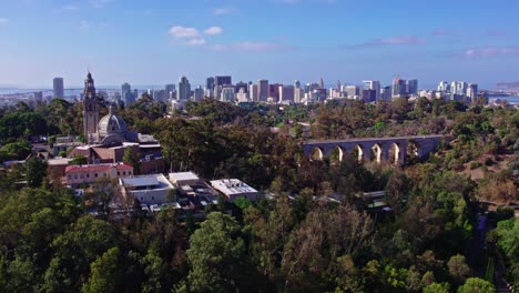 Aerial-View-of-Plane-Landing-in-San-Diego-California,-from-Balboa-Park-bell-tower-Area-Urban-bridge-Streets-Roads-and-Buildings-near-Green-Hill-Park,-Downtown-Cityscape-with-Coronado-bridge-in-Horizon