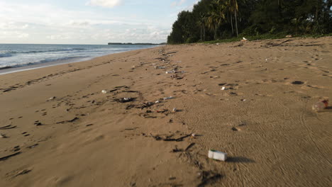 low aerial flying over rubbish washed out on beach, slowly turning into microplastics