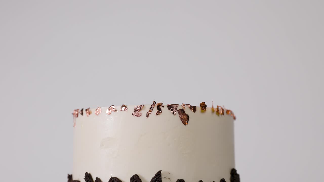 Close-up of a decadent Oreo cake slice topped with shimmering gold foil, ideal for food, dessert, and celebration visuals