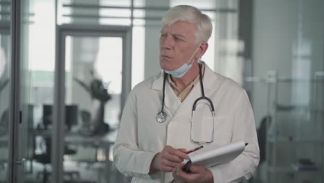 un médico de mediana edad de pelo gris toma notas en un cuaderno