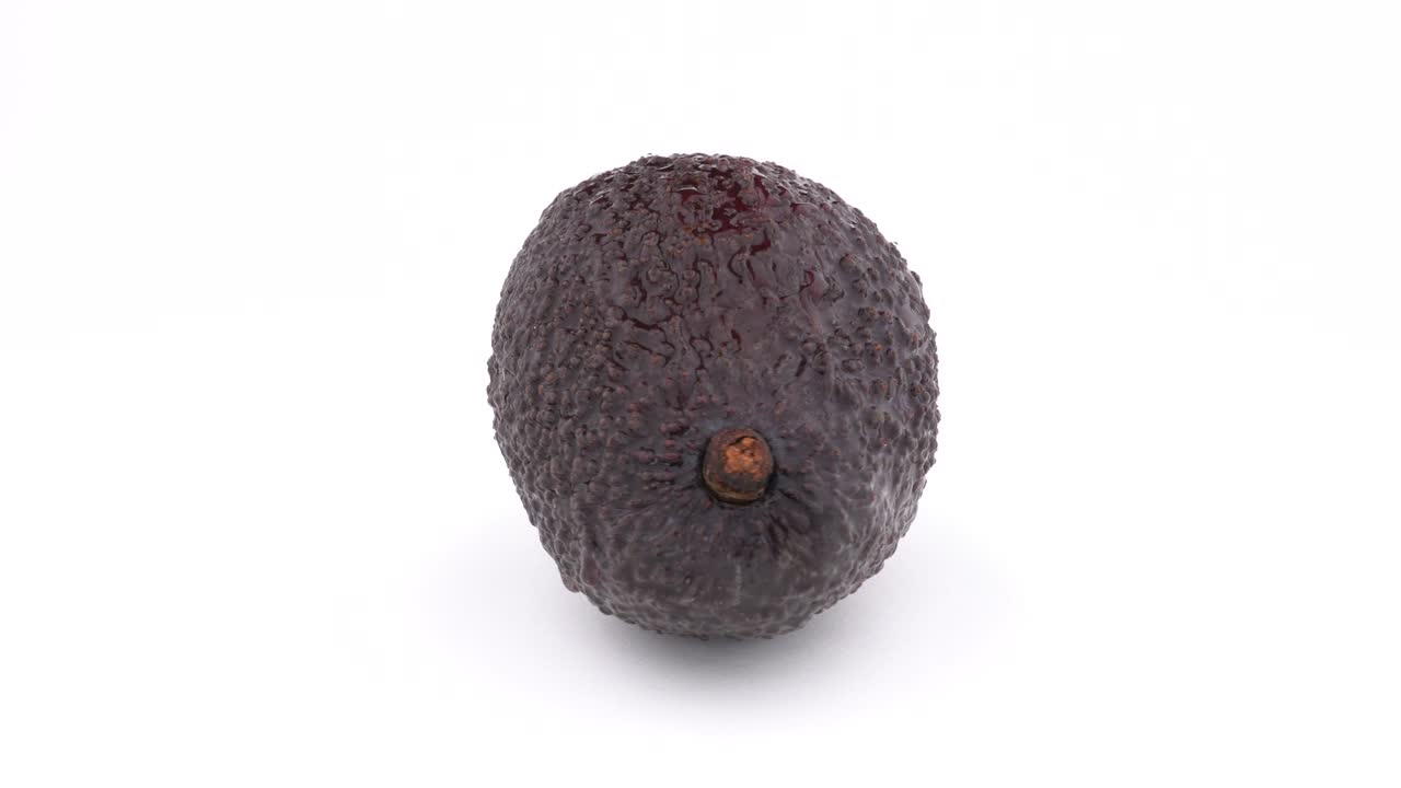 신선한 아보카도는 회전 테이블에서 회전합니다. 색 배경에 고립되어 있습니다. loopable. 클로즈업 매크로.