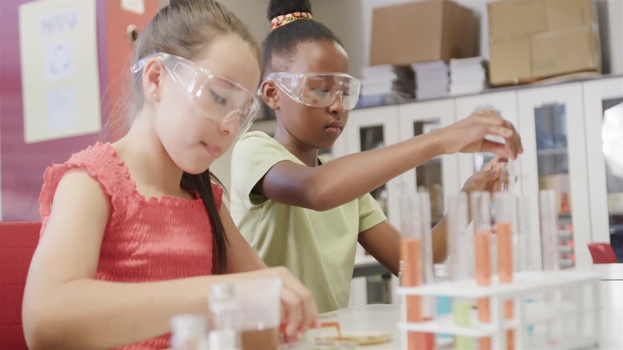 niñas felices y diversas haciendo experimentos en el laboratorio en cámara lenta en la escuela primaria