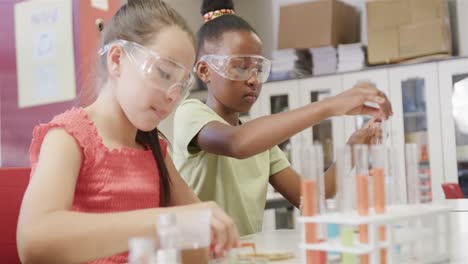niñas felices y diversas haciendo experimentos en el laboratorio en cámara lenta en la escuela primaria