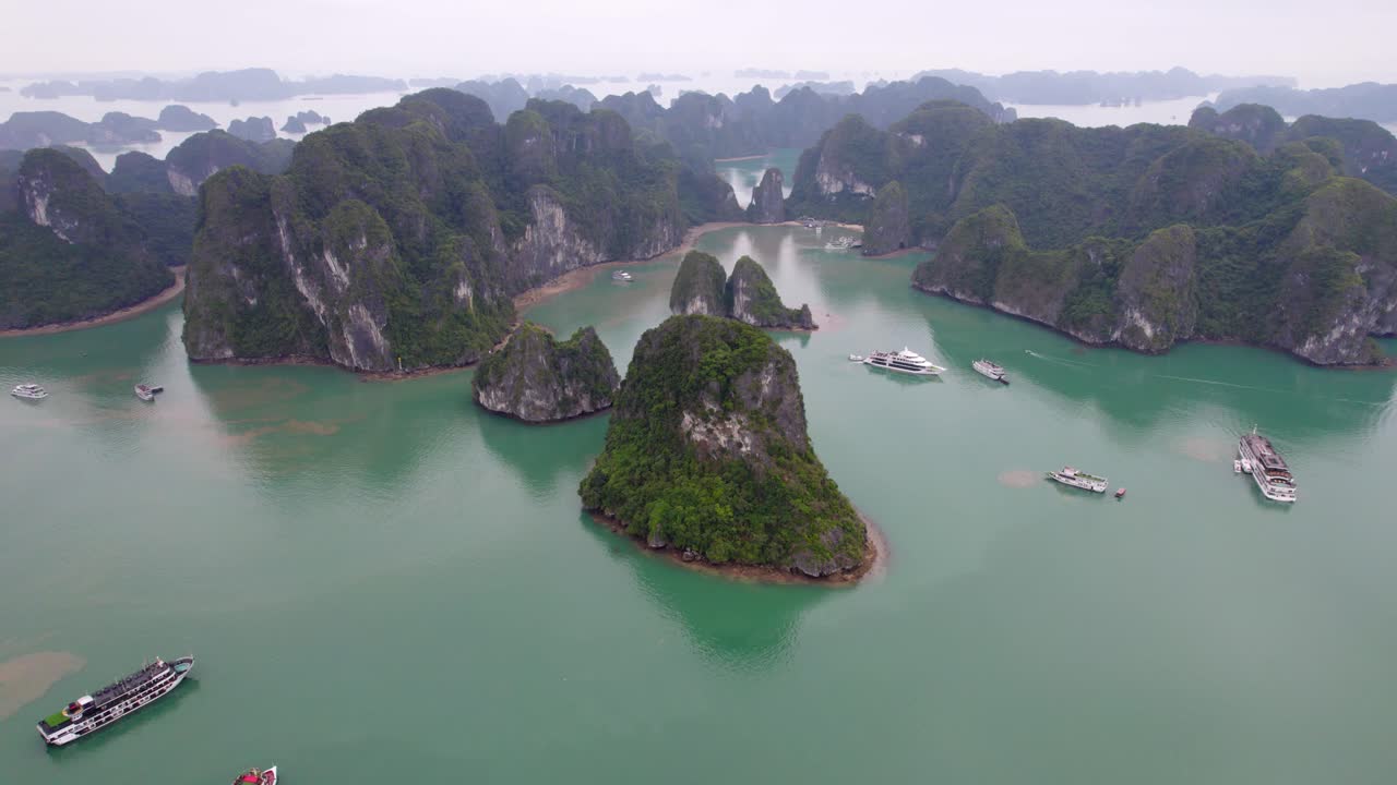 Toàn cảnh từ máy bay không người lái thu về trên các kênh quanh co giữa các vách đá karst có rừng và vịnh yên tĩnh với thuyền và du thuyền neo đậu, Vịnh Hạ Long, Việt Nam