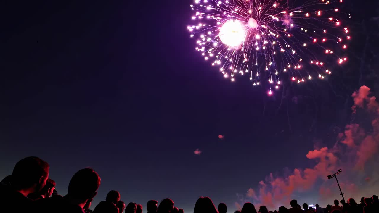 A vibrant fireworks display captured from a low-angle, showcasing colorful bursts against the night