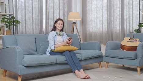 woman relaxing on sofa using smartphone