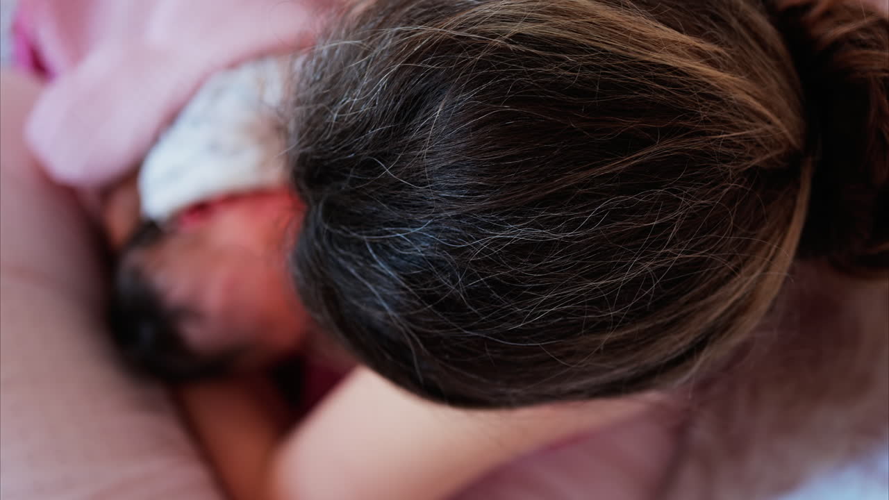 Overhead shot of a mother breastfeeding her newborn baby in a quiet, nurturing environment