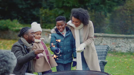 family having fun with sparklers in autumn garden at home - shot in slow motion