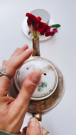 woman holding teapot with ring and red flowers