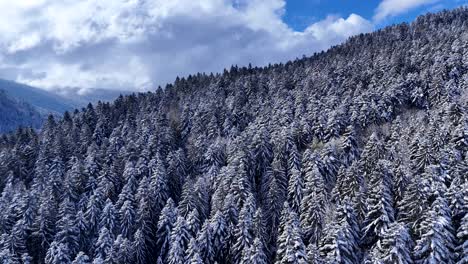 Drohnenansicht-über-Dem-Bergkamm-Mit-Schneebedeckter-Landschaft-Im-Frühling-Mit-Blauem-Himmel-Und-Großen-Wolken