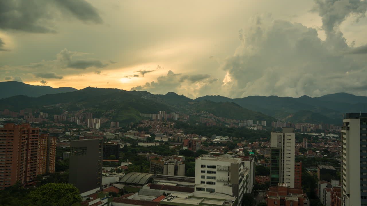 Stunning aerial footage of Medellin's cityscape at sunset, capturing dramatic clouds and mountainous terrain under warm golden light. Perfect for urban and nature-themed projects. Timelapse