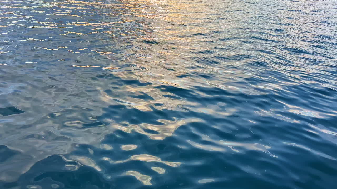 Water surface reflects light during evening hours near a calm shoreline with gentle waves showing movement and texture