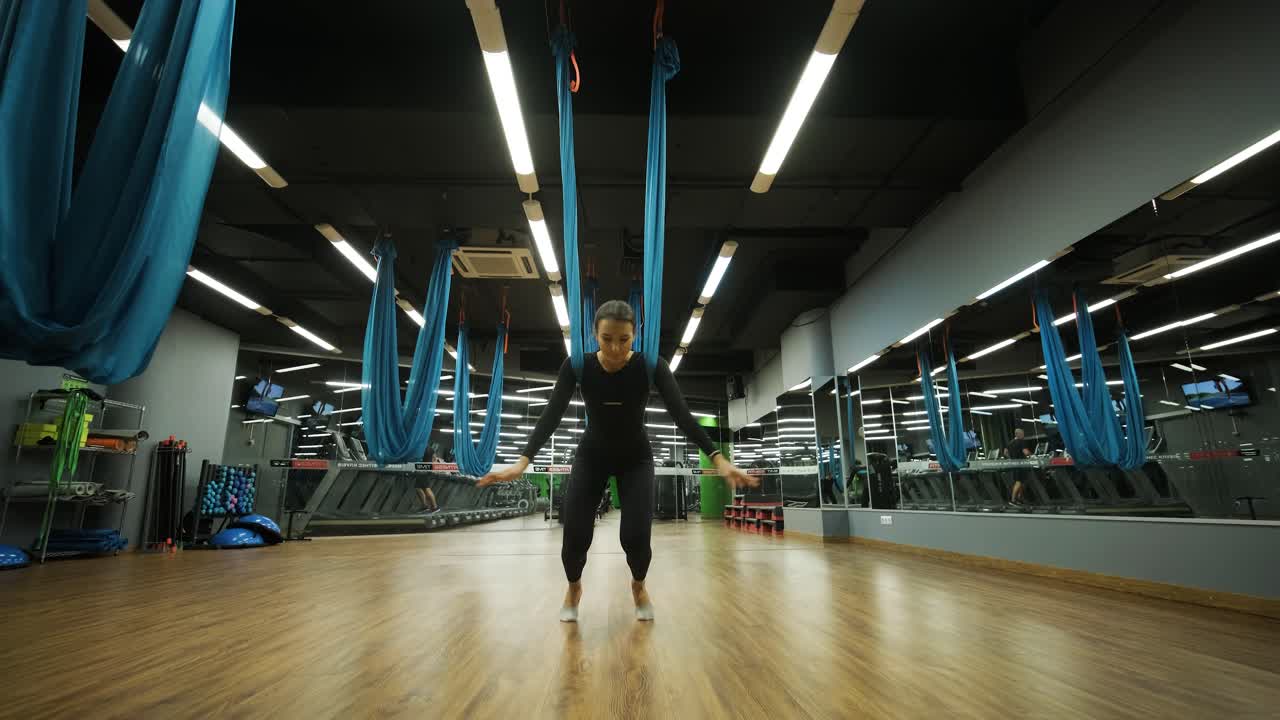 Attractive woman doing aero yoga stretching exercises in hammocks at fitness Studio. Healthy lifestyle for female. Workout gym