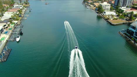 two speedboats racing along a canal in the shadows of luxurious surfers paradise apartments and luxury waterfront houses