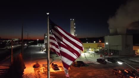 Bandera-Americana-Ondeando-Frente-A-Una-Planta-Química-Industrial-Por-La-Noche