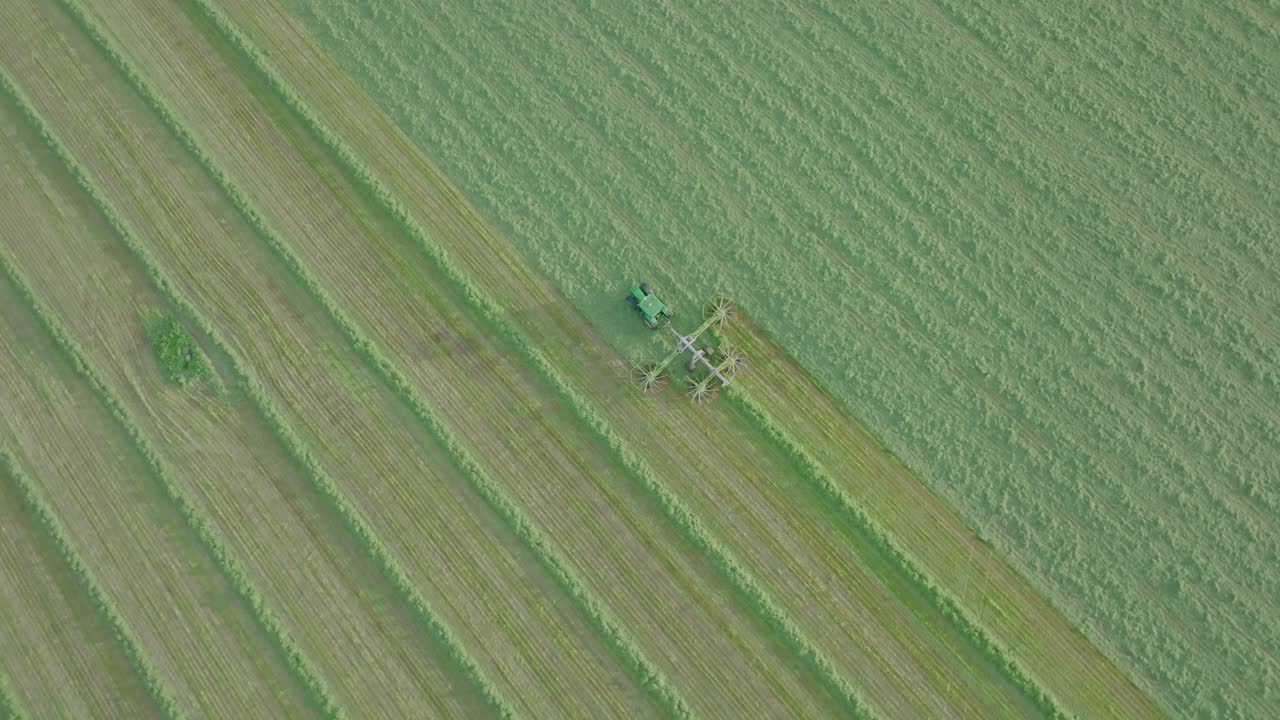 toma de seguimiento aérea giratoria de un agricultor cortando ensilaje en un día cálido y soleado, escocia