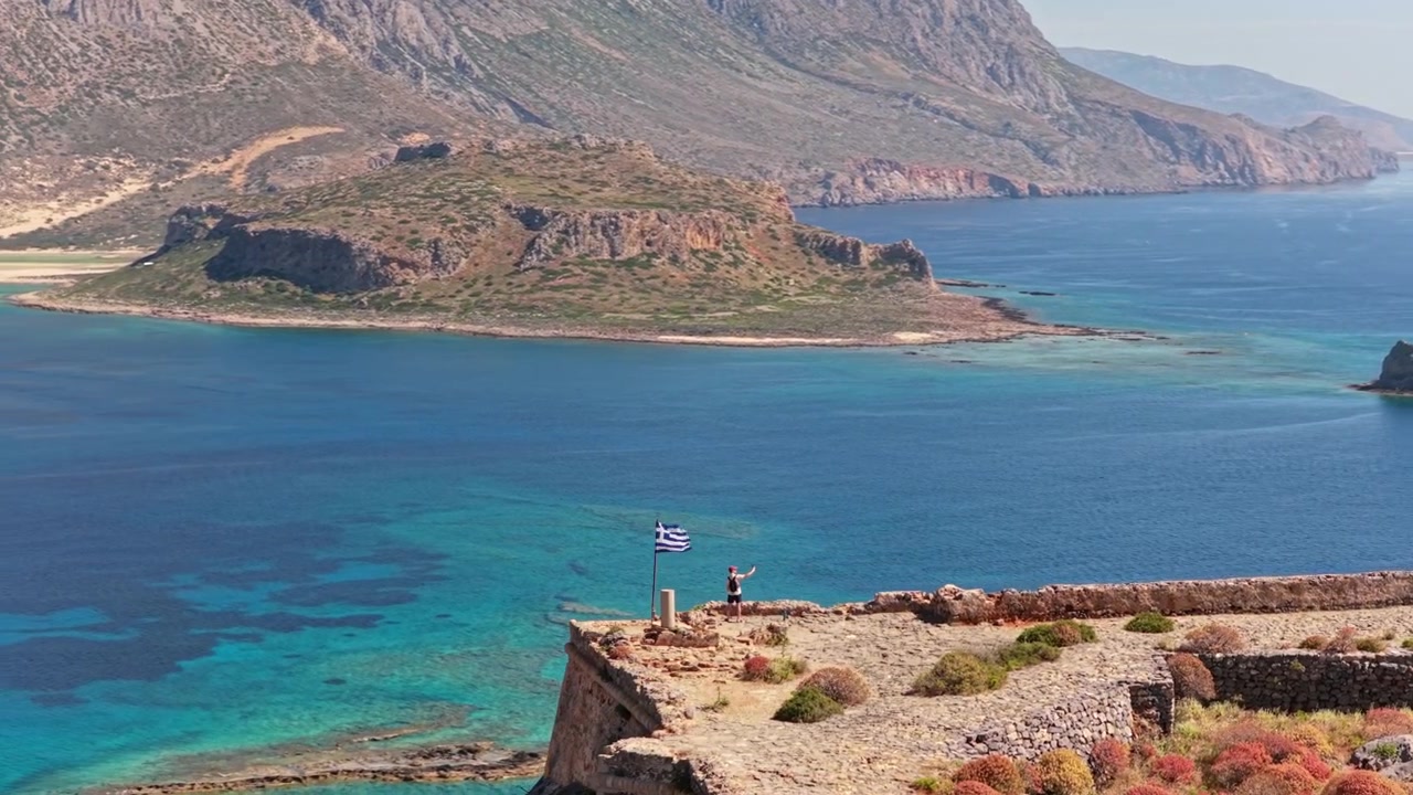 Vue aérienne par drone d'un drapeau grec sur le plateau de la forteresse de l'île de Gramvousa au-dessus de la mer d'un bleu profond, Gramvousa, Grèce