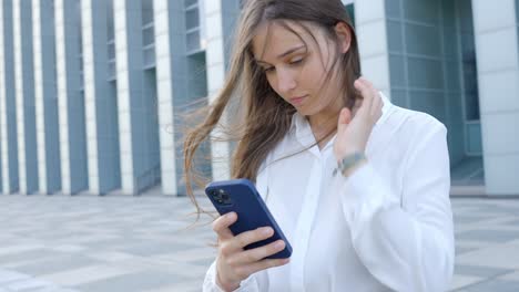 Beautiful-young-entrepreneur-female-using-smartphone-outside-office