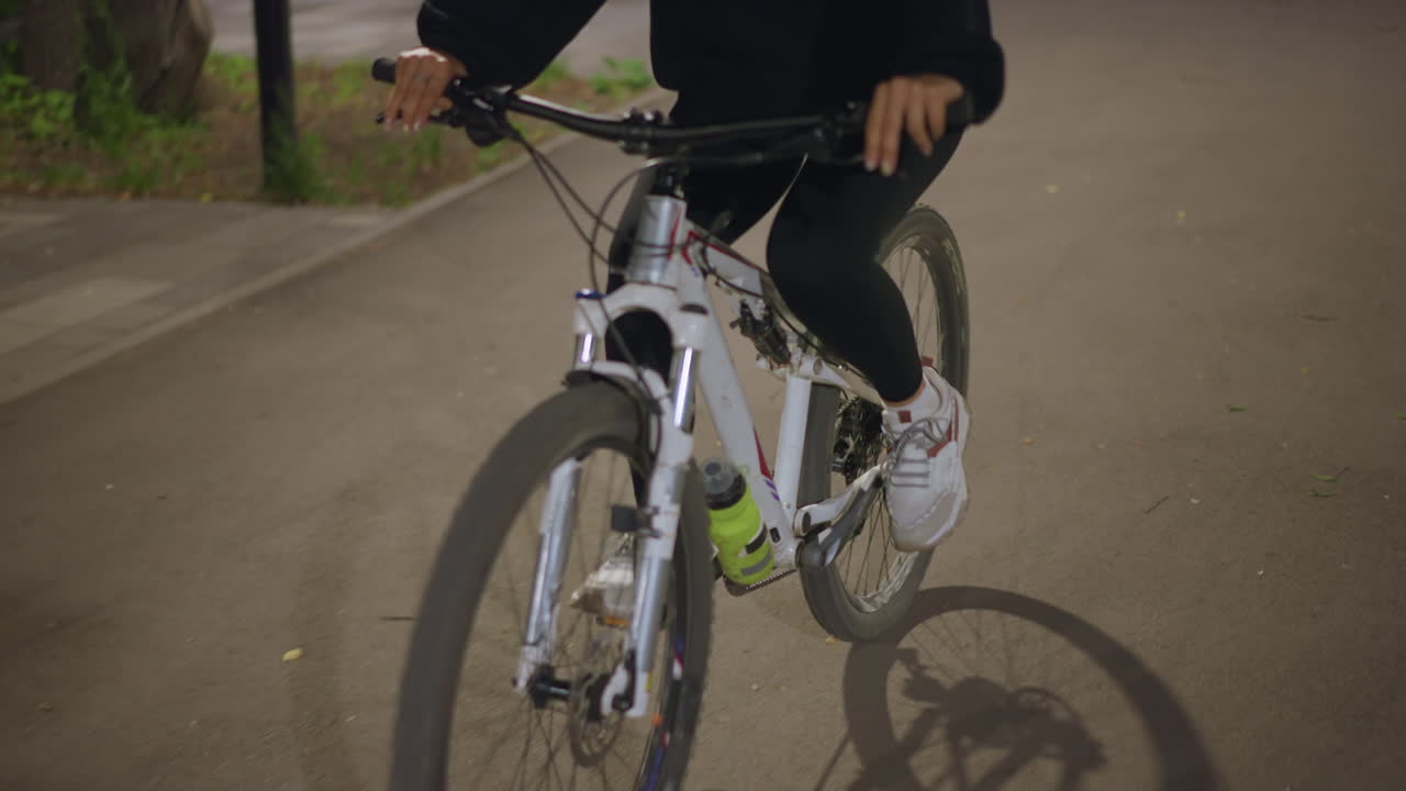 Steady Cyclist Holding Handlebars With Shadowed Wet Streets Illuminated, Rider Maintains Balanced Posture Gripping Handlebars During Night Ride With Illuminated Wet Pavement Shadows