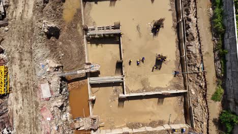aerial view of a construction site with workers building a foundation next to a completed building with a pool