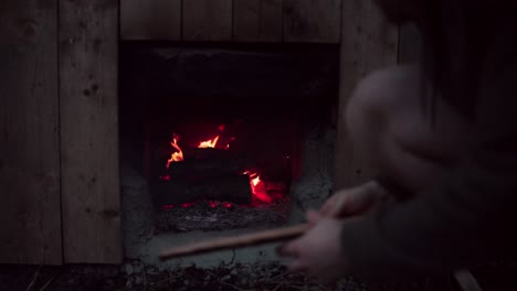 man putting firewood on fire under hot tub