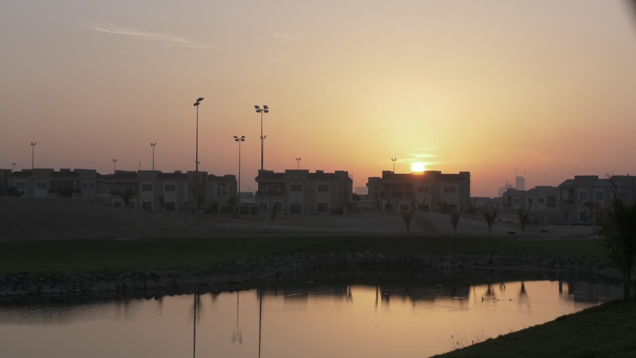 puesta de sol detrás de los edificios por la noche, atardecer, sobre casas en la ciudad del medio oriente de dubai - emiratos árabes unidos