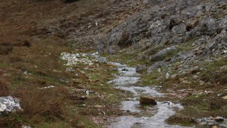 a small stream flowing through a polluted landscape filled with trash and debris