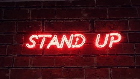 neon sign displaying stand up on a red brick wall flickers on and off, creating a vibrant and dynamic atmosphere