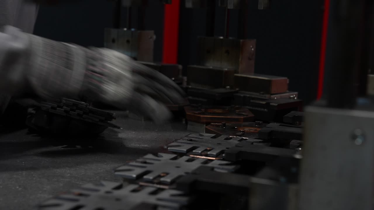 Manual manufacturing process showing worker placing metal washers in machine as part of precise production step, focused on accurate positioning, controlled handling and consistent mechanical workflow