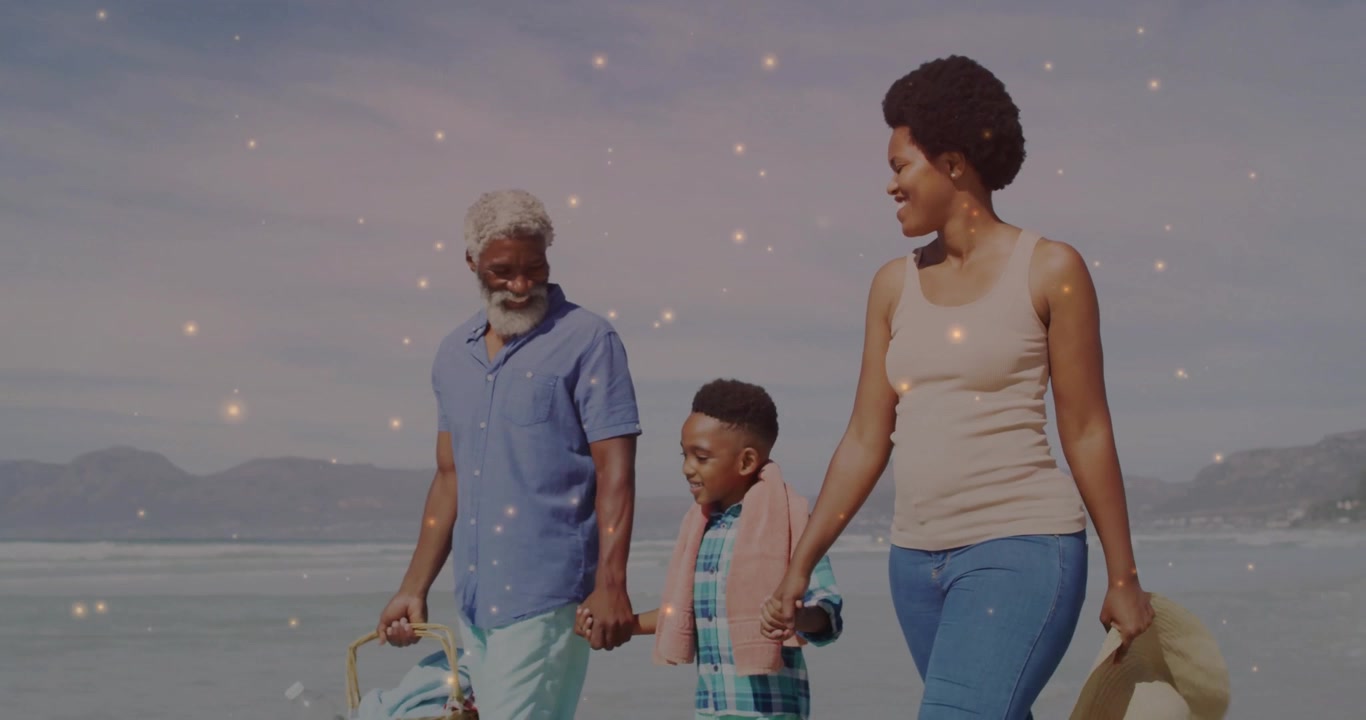 Under sunlight family carrying picnic basket walking through waves for health with sparkle overlay
