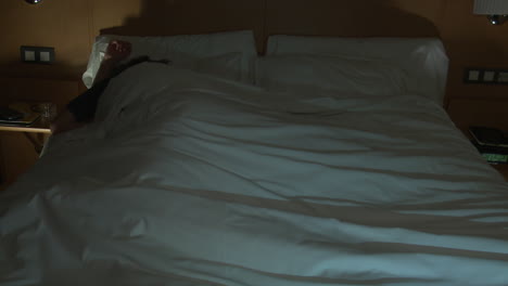 man sleeping in a hotel bed at night