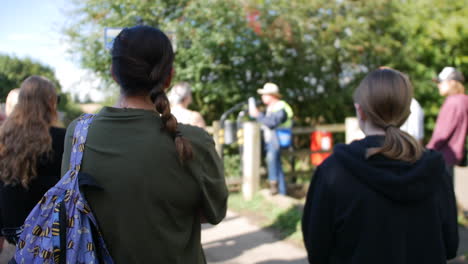 a group of people is gathered outdoors on a tour, listening to a guide who is speaking in the background. an educational or touristic experience, with attendees focused on the presentation