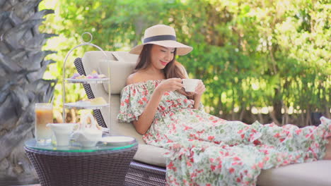 beautiful asian woman with hat having afternoon tea at a luxury resort