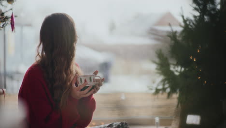 happy woman smelling fresh coffee by window during christmas