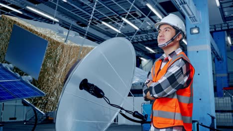 ingeniero observando antenas parabólicas y paneles solares en una fábrica.