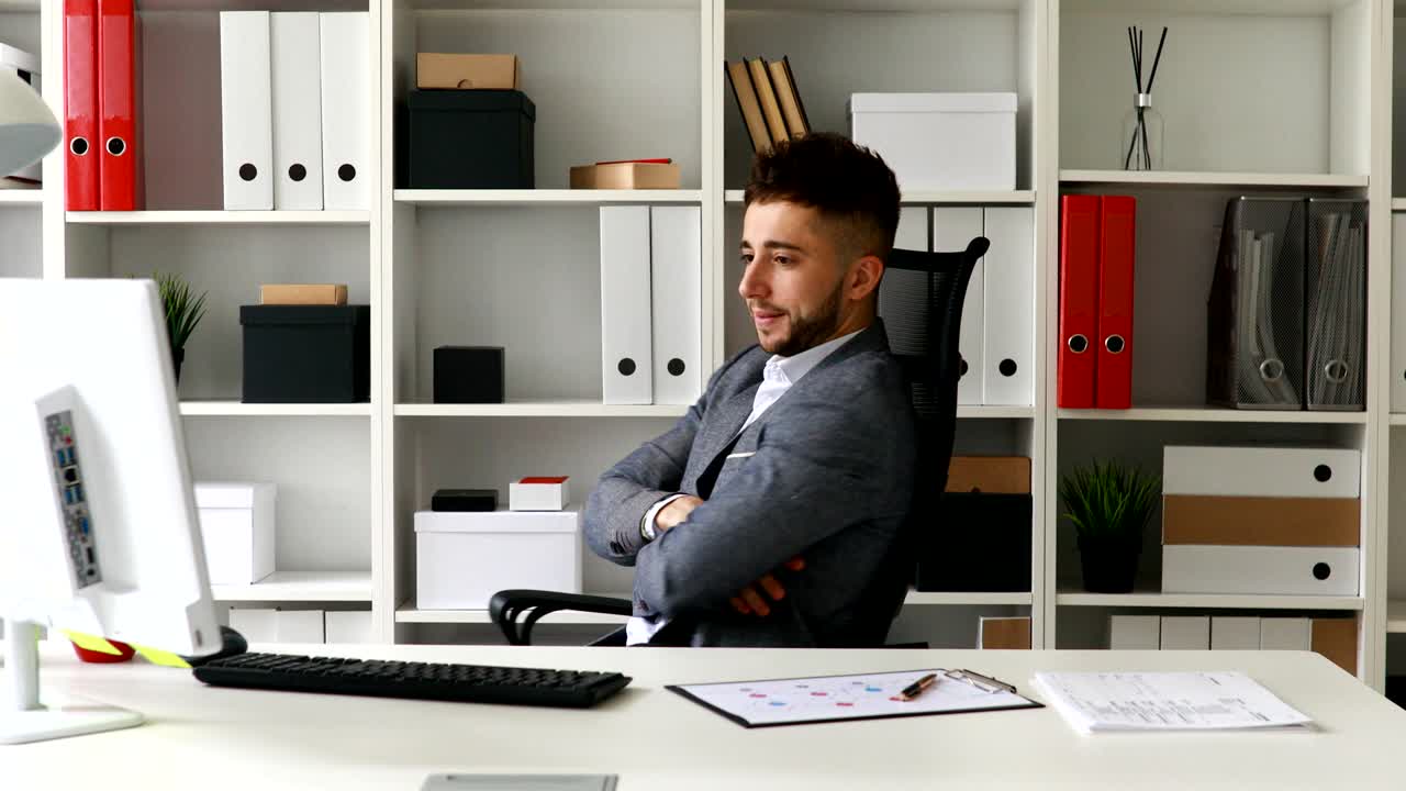 Giovane uomo d'affari che gira sulla sedia da ufficio esultando per il successo