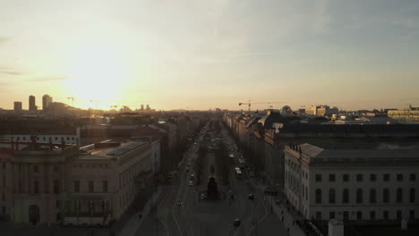 Aéreo:-Vuelo-Panorámico-Bajo-A-Través-De-La-Concurrida-Calle-Berlín,-Alemania-Hacia-La-Puerta-De-Brandenburgo-En-Una-Hermosa-Luz-épica-De-Puesta-De-Sol