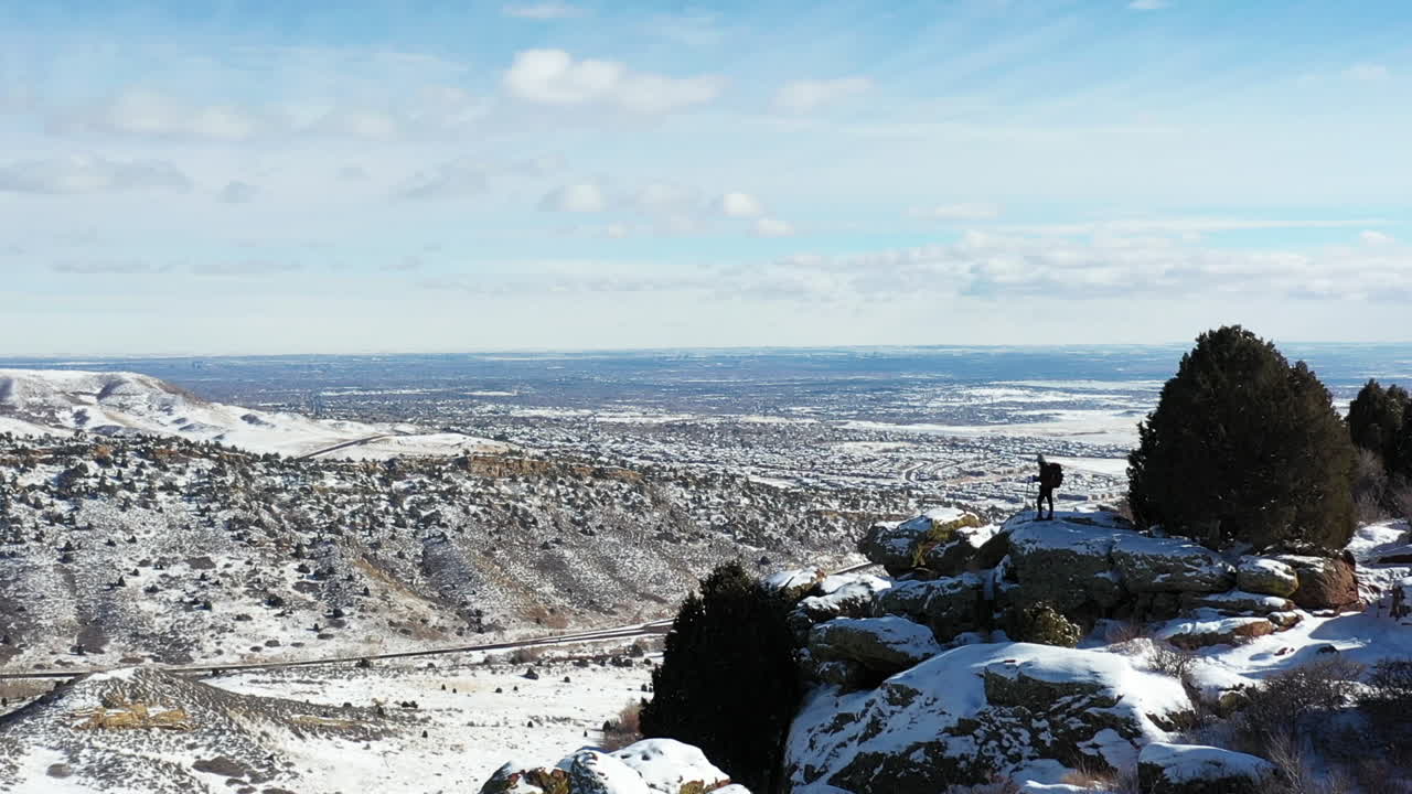 vista aérea de una persona solitaria parada en la cima de una colina con una vista increíble del paisaje invernal de la cordillera de las montañas rocosas, colorado, ee.uu.