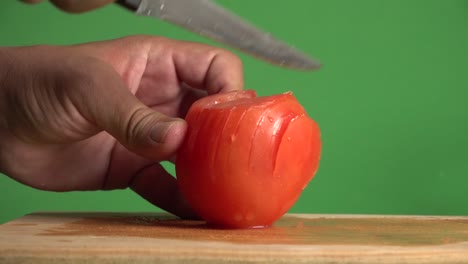 hands cutting in slices a tomato on a chroma background