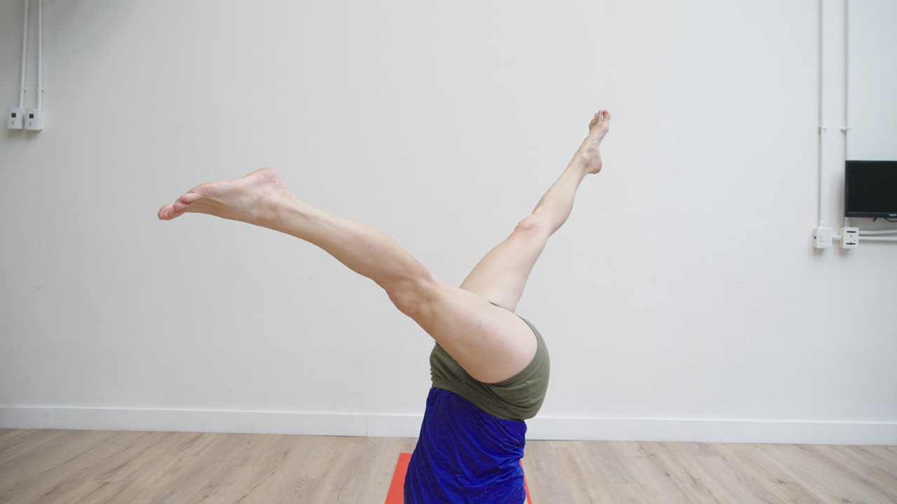 Woman Performing Headstand Yoga Pose with Legs Spread in Studio