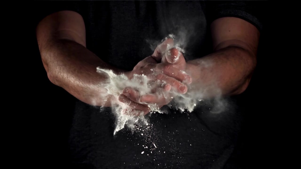 Slowmotion af klappende hænder, der skaber en sky af hvidt pulver